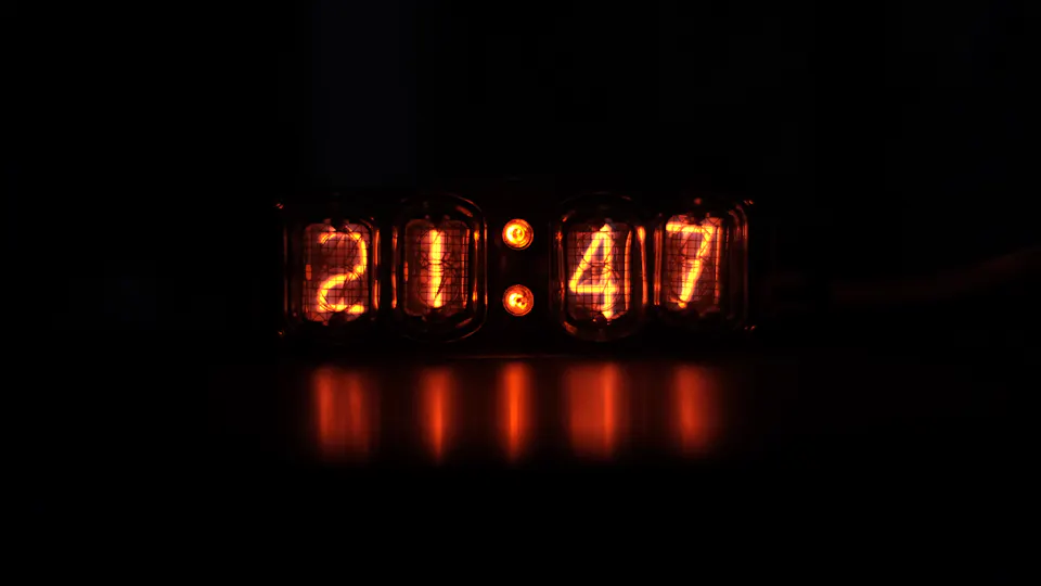 A digital clock with glowing red digits in a dark room