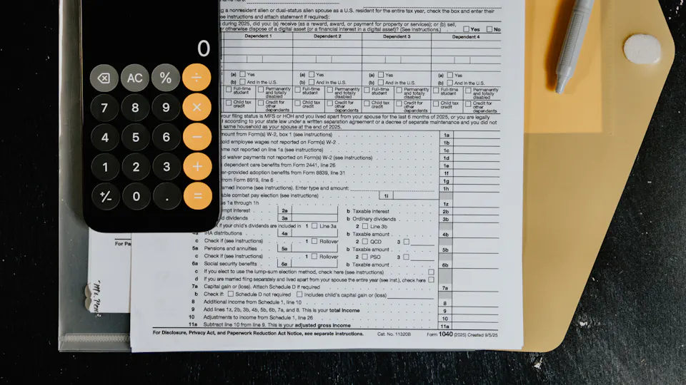 Tax forms on a desk with a calculator and a pen